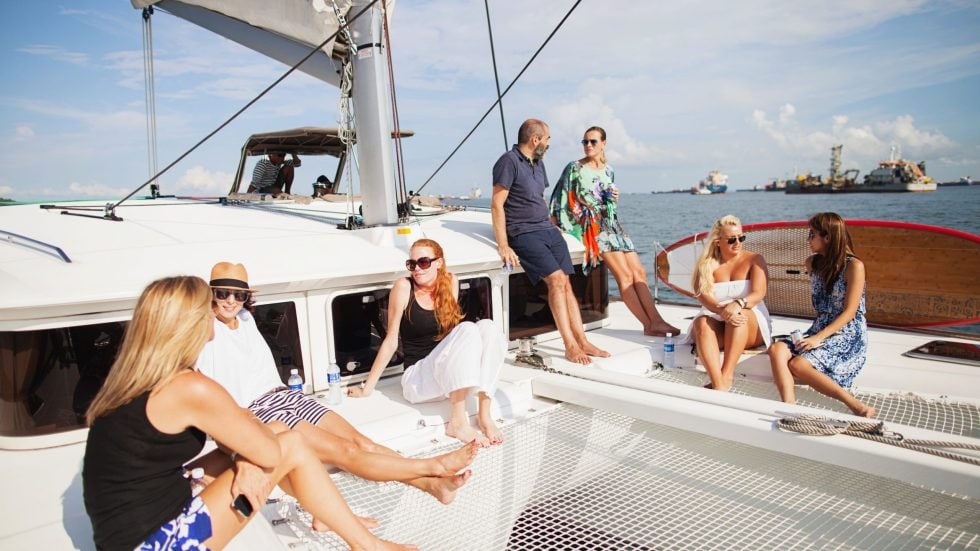 Guests relaxing on the deck of an Infinity Sails catamaran in Singapore